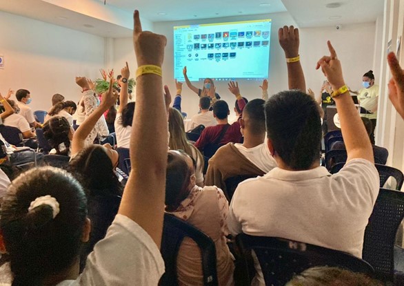personas sentadas en un auditorio levantando las manos