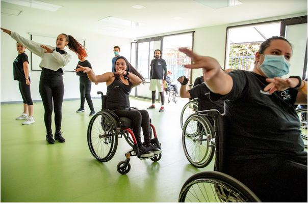 En la foto: Aura Lorena Varela, en silla de ruedas, bailando con varias personas, algunas caminantes y otras en sillas de ruedas.